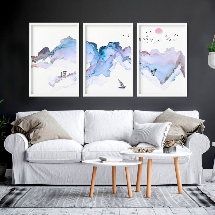 Three framed art prints with watercolour mountain landscapes displayed above a white sofa in a modern living room.