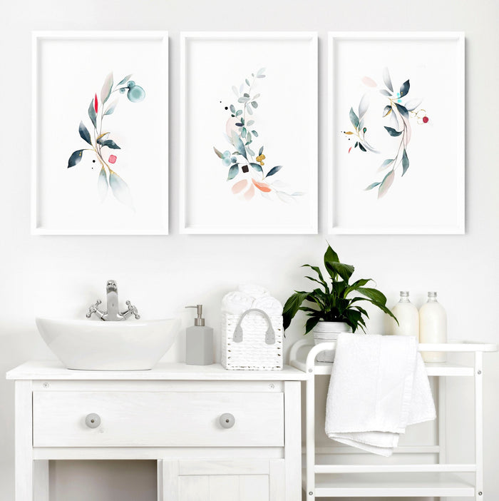 Three framed botanical bathroom prints displayed above a white vanity sink in a minimalist bathroom setting.