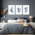 Modern blue grey walls bedroom with three framed botanical floral prints above bed