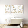 Three framed gold botanical prints displaying relax, refresh and renew above a freestanding bathtub